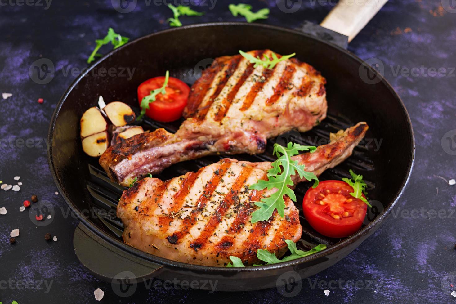 Raw pork steak with herbs on dark background. Raw juicy steak on bone photo