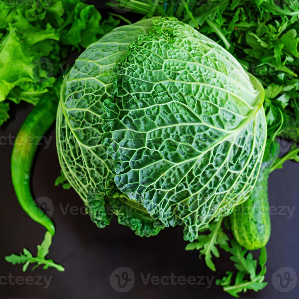 Savoy cabbage with pepper and greens on dark background photo