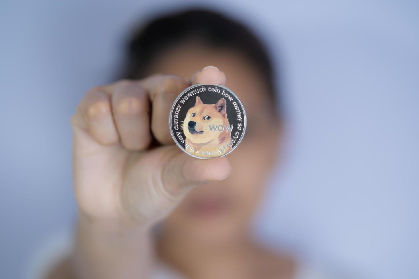 Dogecoin DOGE included with Cryptocurrency on hand working asian women holding coin in front face Filed and put and give to me. Blockchain technology future is money Close up Dogecoin concept. photo