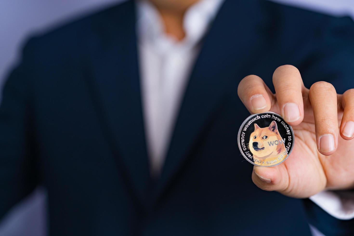 Dogecoin DOGE included with Cryptocurrency on hand business man wearing a blue suit. Filed and put and give to me. photo