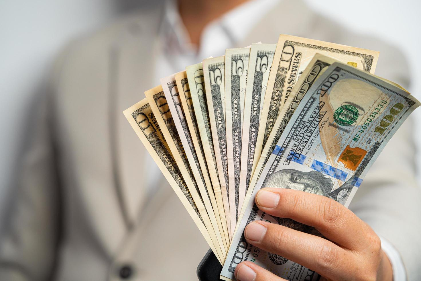 Business man and money in us dollar hold on hand wearing a brown suit jacket and Give to me USD, Pay, exchange money on white background. Business finance and bank employee Concept. photo