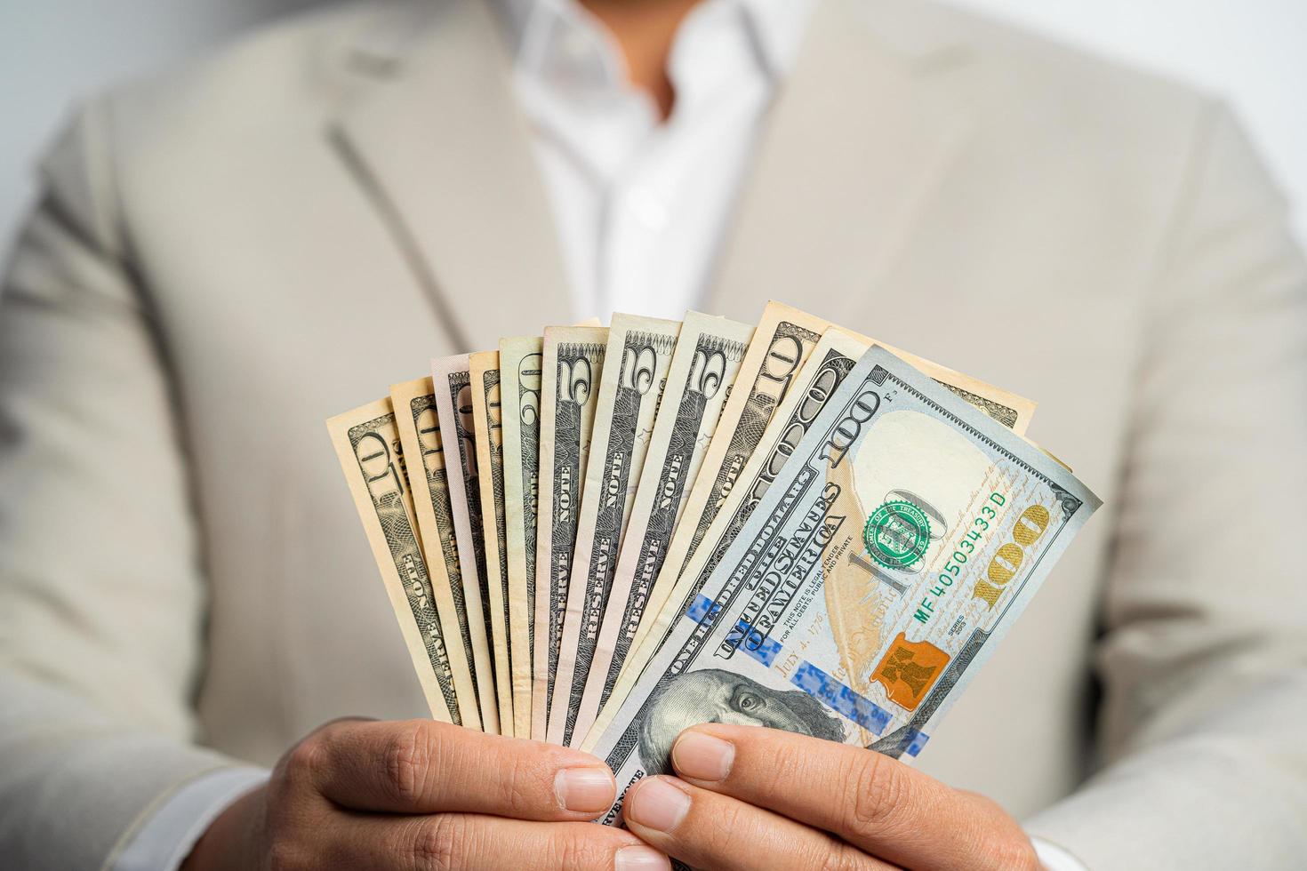 Business man and money in us dollar hold on hand wearing a brown suit jacket and Give to me USD, Pay, exchange money on white background. Business finance and bank employee Concept. photo