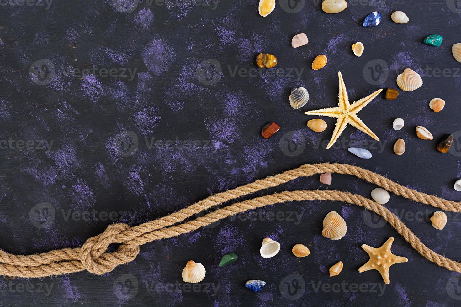 Seashell, starfish and rope on dark background. Top view photo