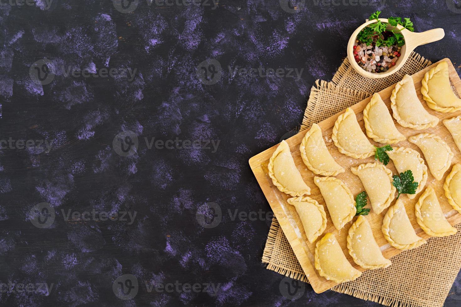 Delicious dumplings with cabbage on dark background. Top view photo