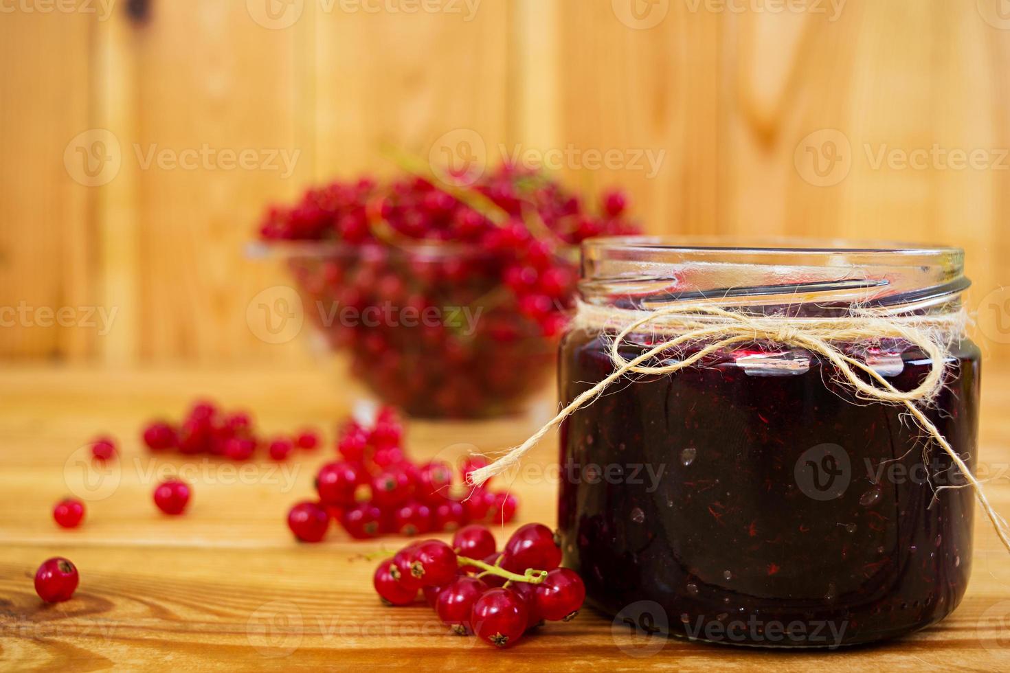 tarro con mermelada de grosella roja sobre un fondo de madera foto