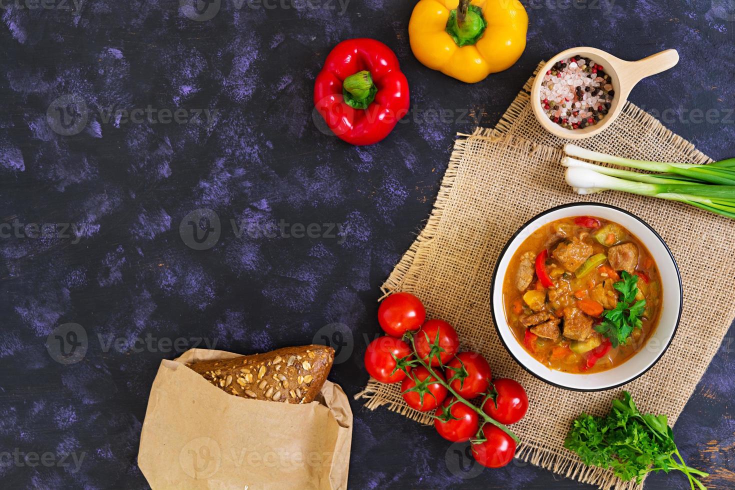 Stew with meat and vegetables in tomato sauce on dark background photo