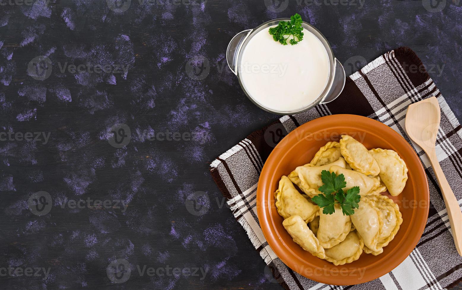 Delicious dumplings with cabbage on dark background. Top view photo