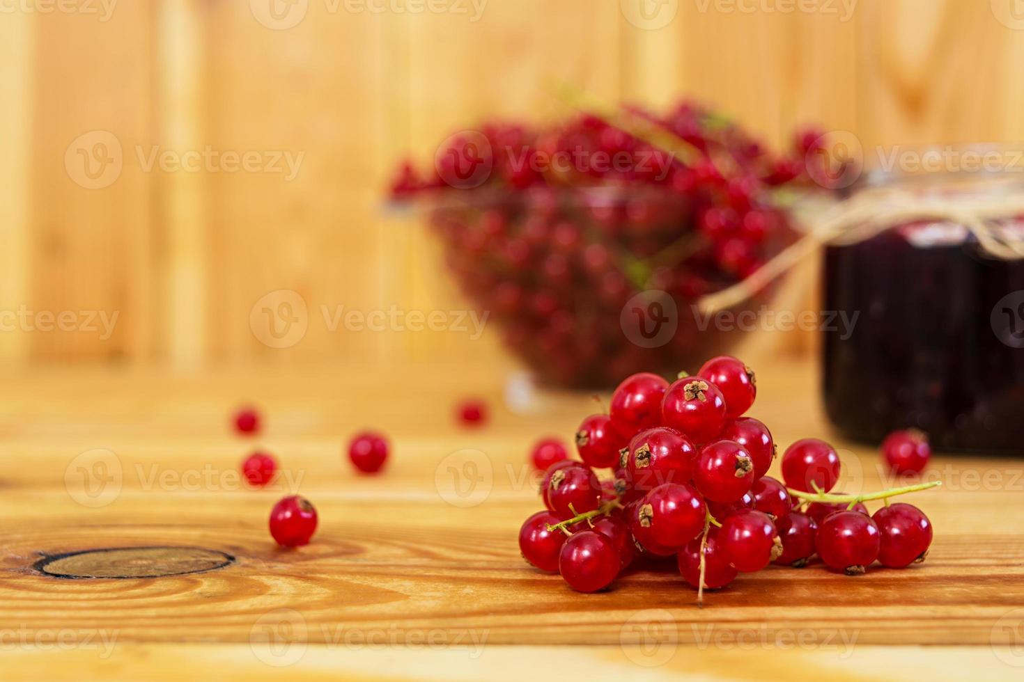 Jar with jam of red currant on a wooden background photo