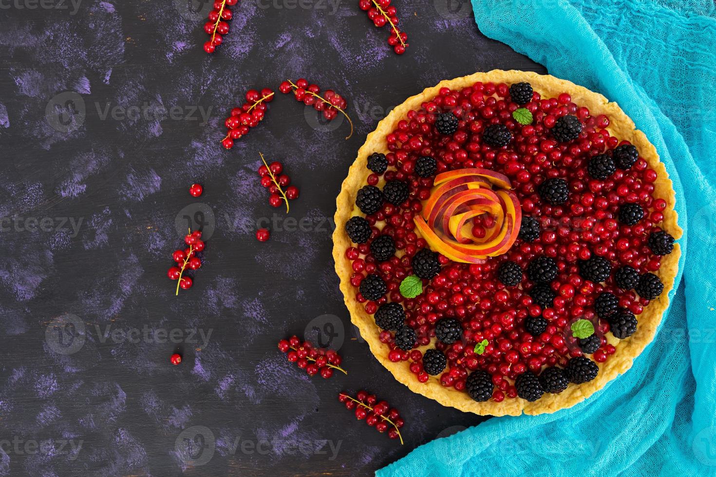 Delicious tart with red currants, peach and blackberries. Top view photo