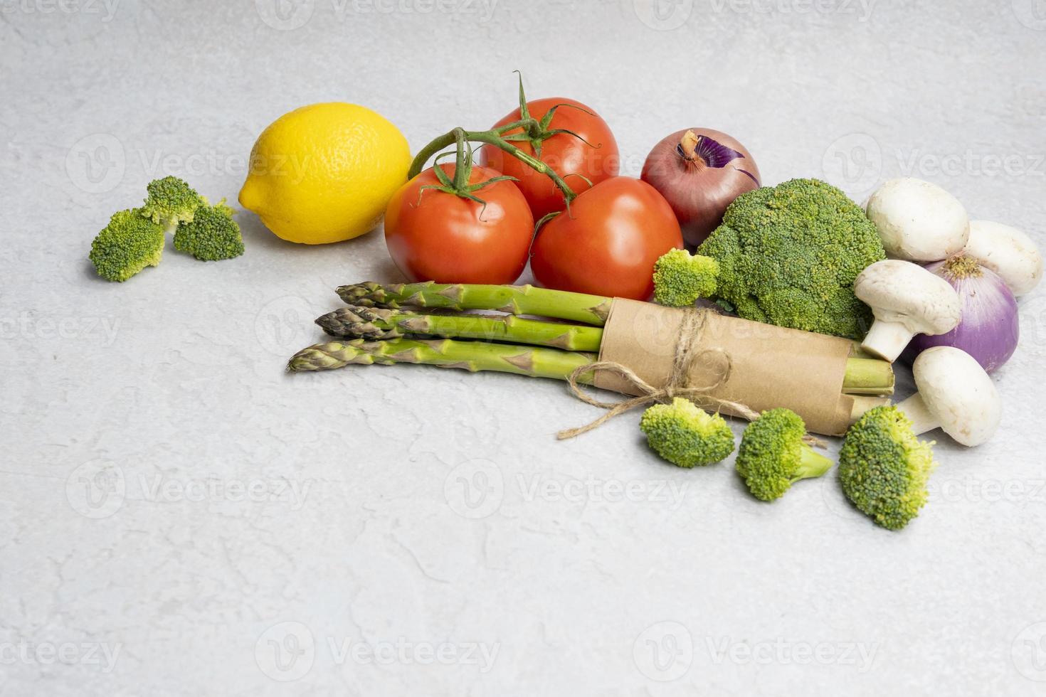 Group of organic fresh vegetables - green asparagus, broccoli, mushrooms on grey background, close-up. photo