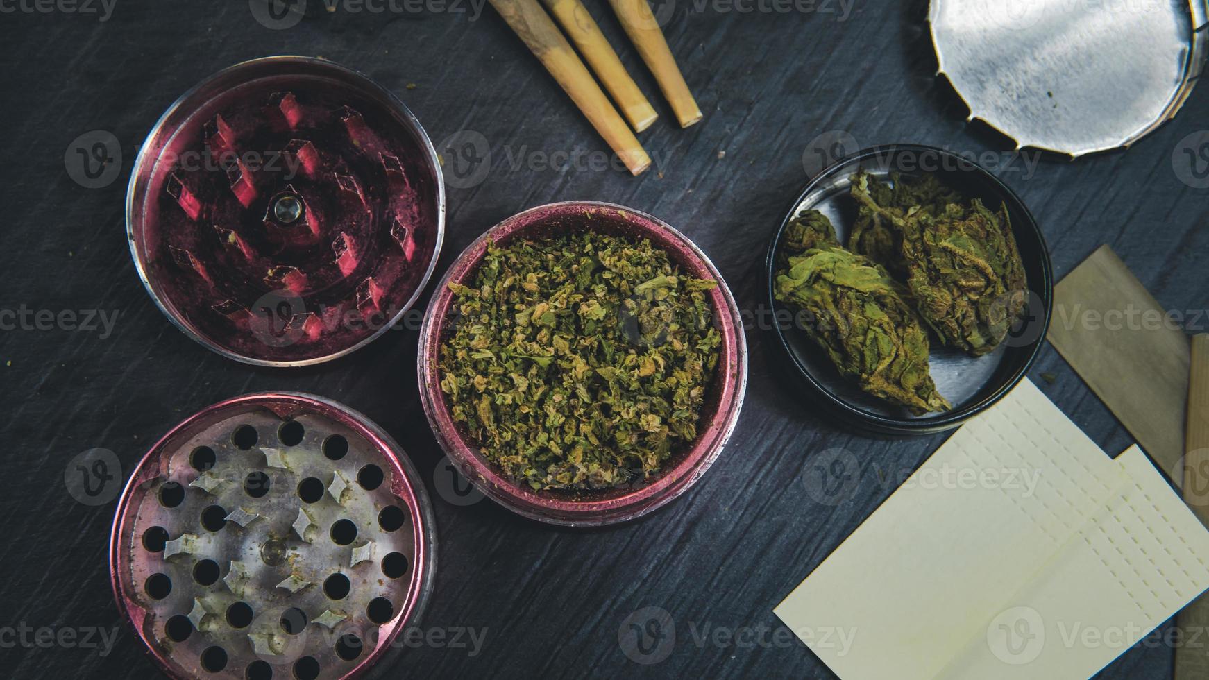 Marijuana buds, joints, paper and lighter lie on dark grey background. photo