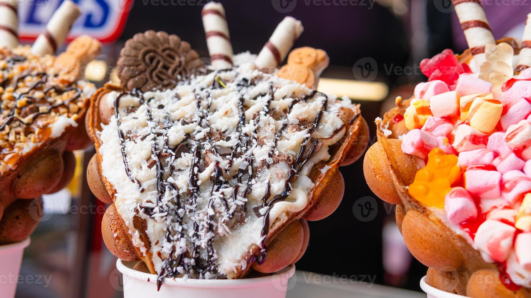 Bubble waffles with raspberries, chocolate and marshmallow in white paper cups are sold on Open kitchen food festival event. Hong kong waffles. photo