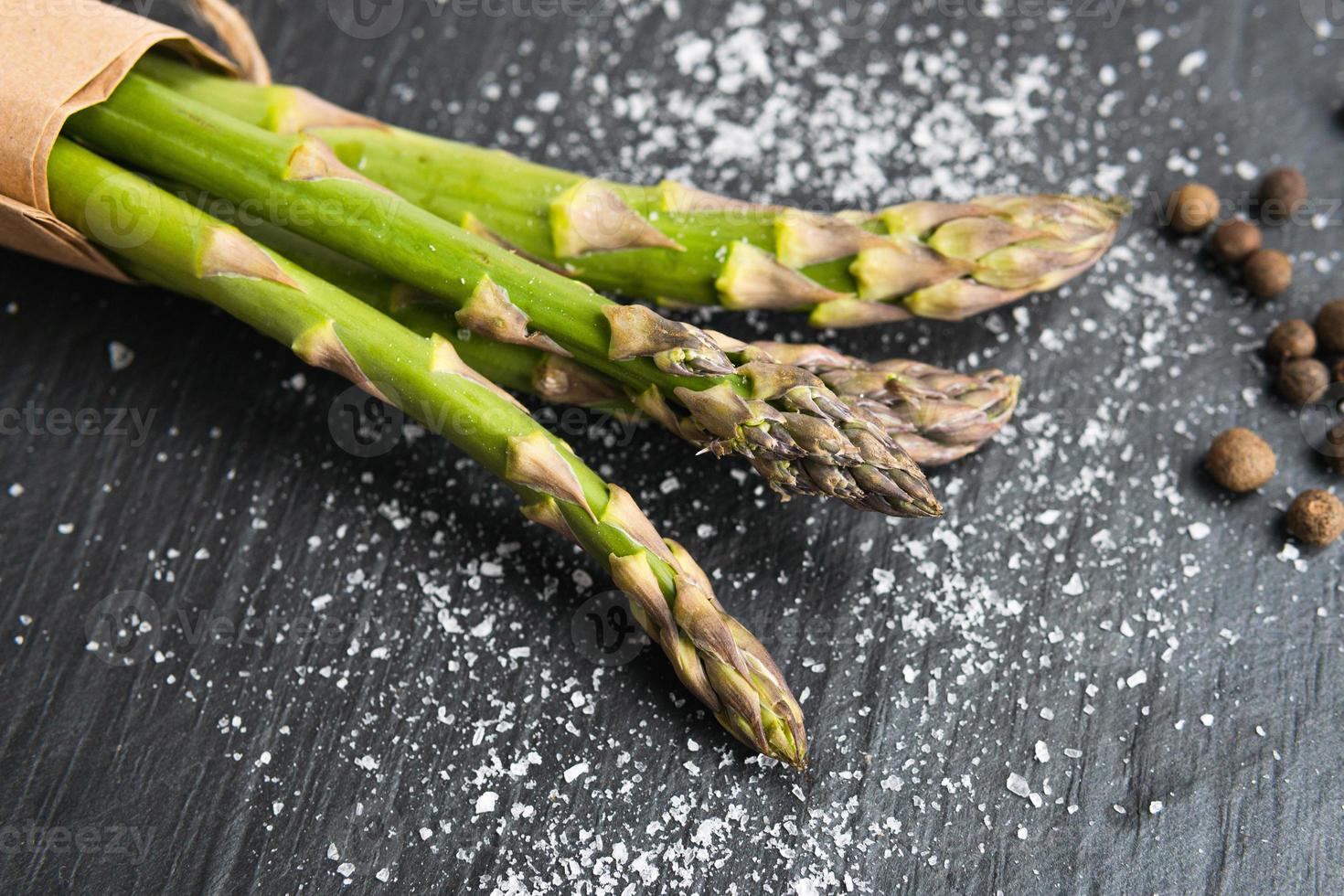 primer plano de espárragos verdes frescos orgánicos con sal y pimienta. concepto de comida vegetariana saludable, dieta y cocina casera. foto