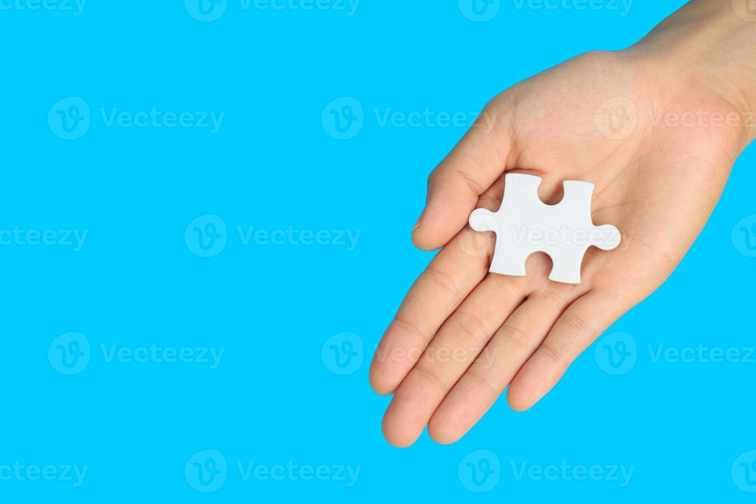 white jigsaw puzzle pieces in  hand on blue background, The last piece of jigsaw puzzle, Copy space. photo