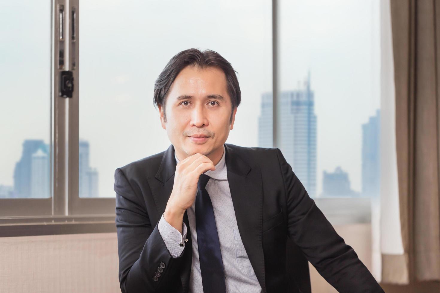 Smiling business man sitting at office desk and looking at camera photo