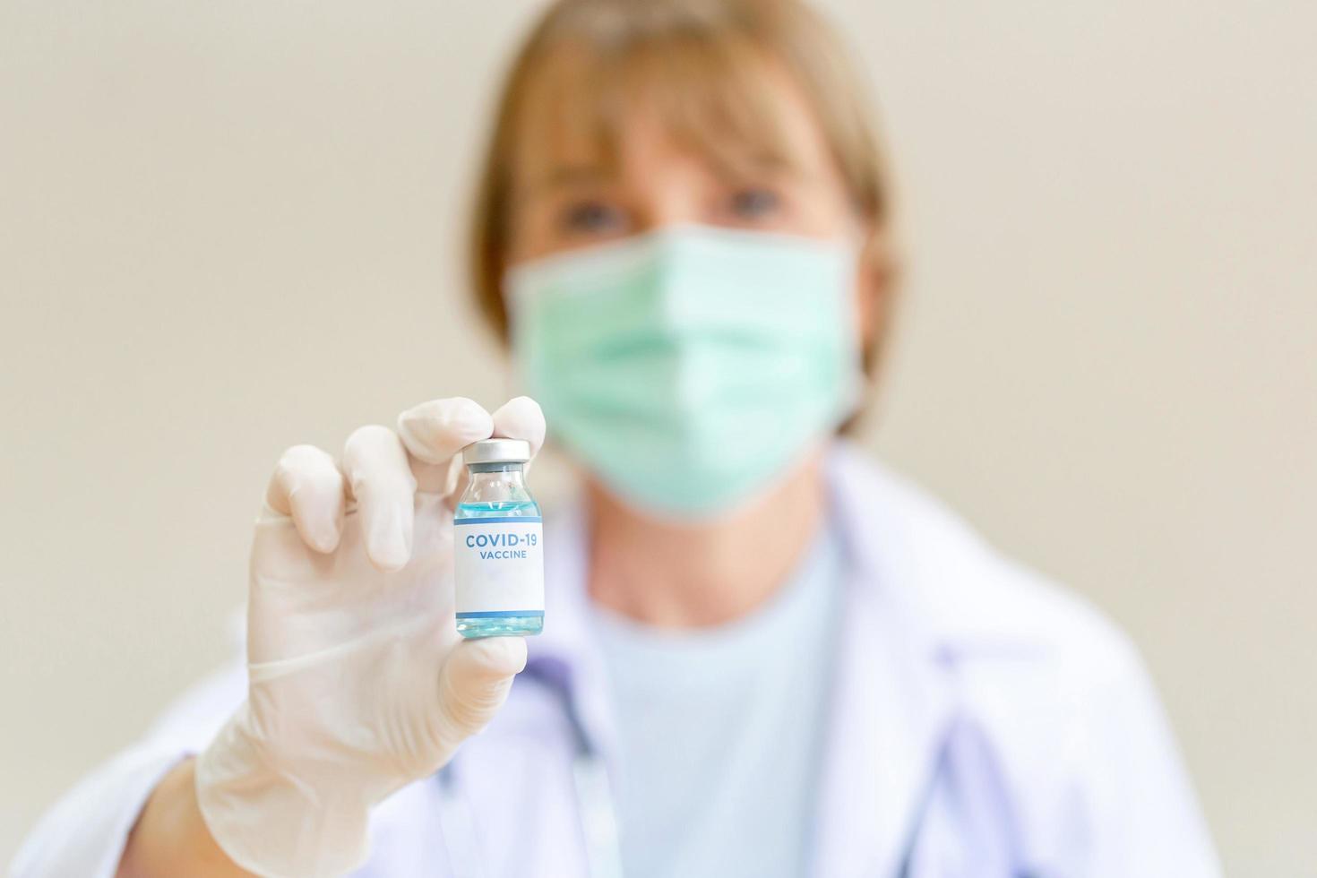 Close up of female doctor wearing medical protective face mask holding COVID-19 vaccine, Healthcare and Medical concepts photo