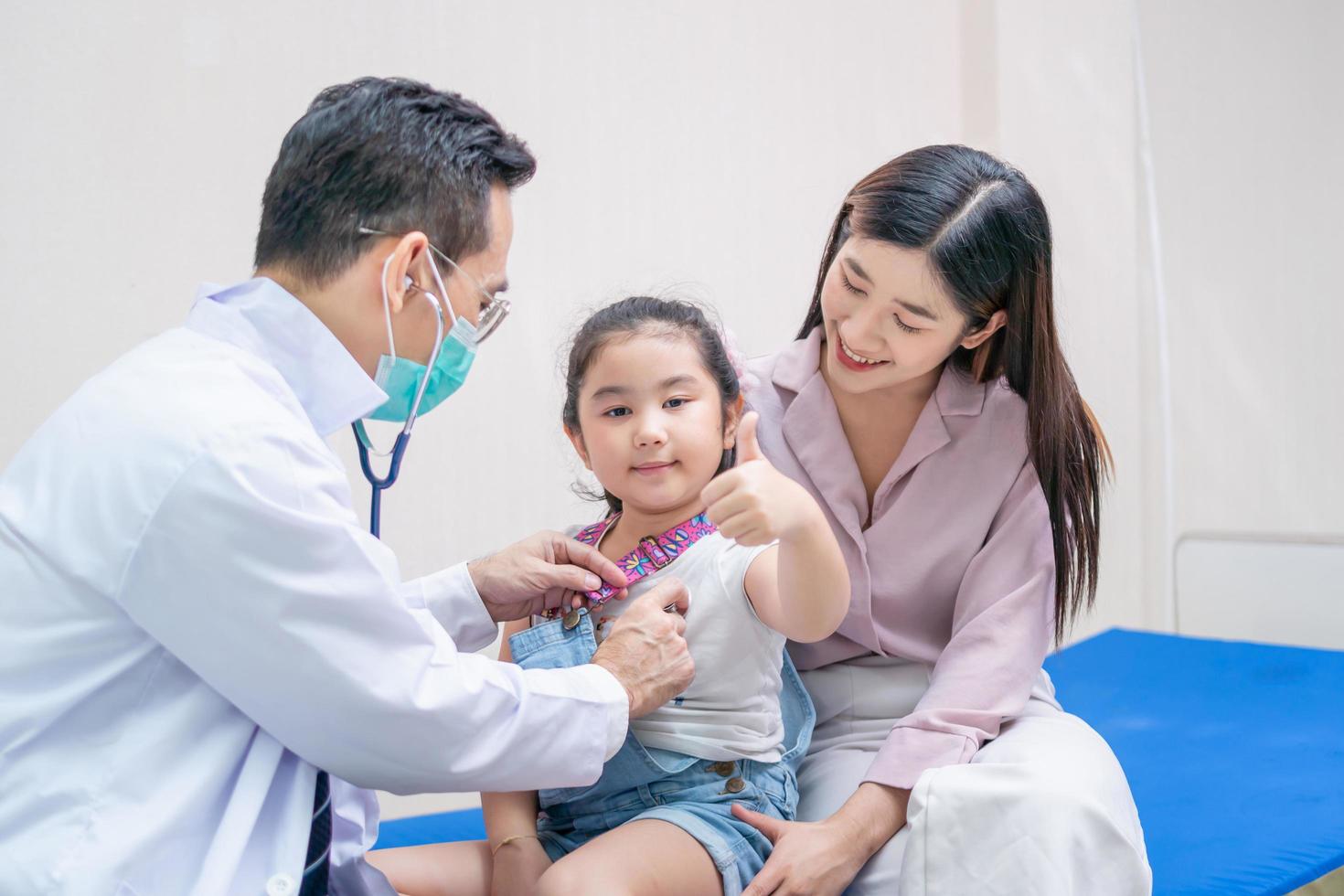 niño niña paciente visita al médico con la madre, médico pediatra que examina al pequeño paciente usando un estetoscopio foto