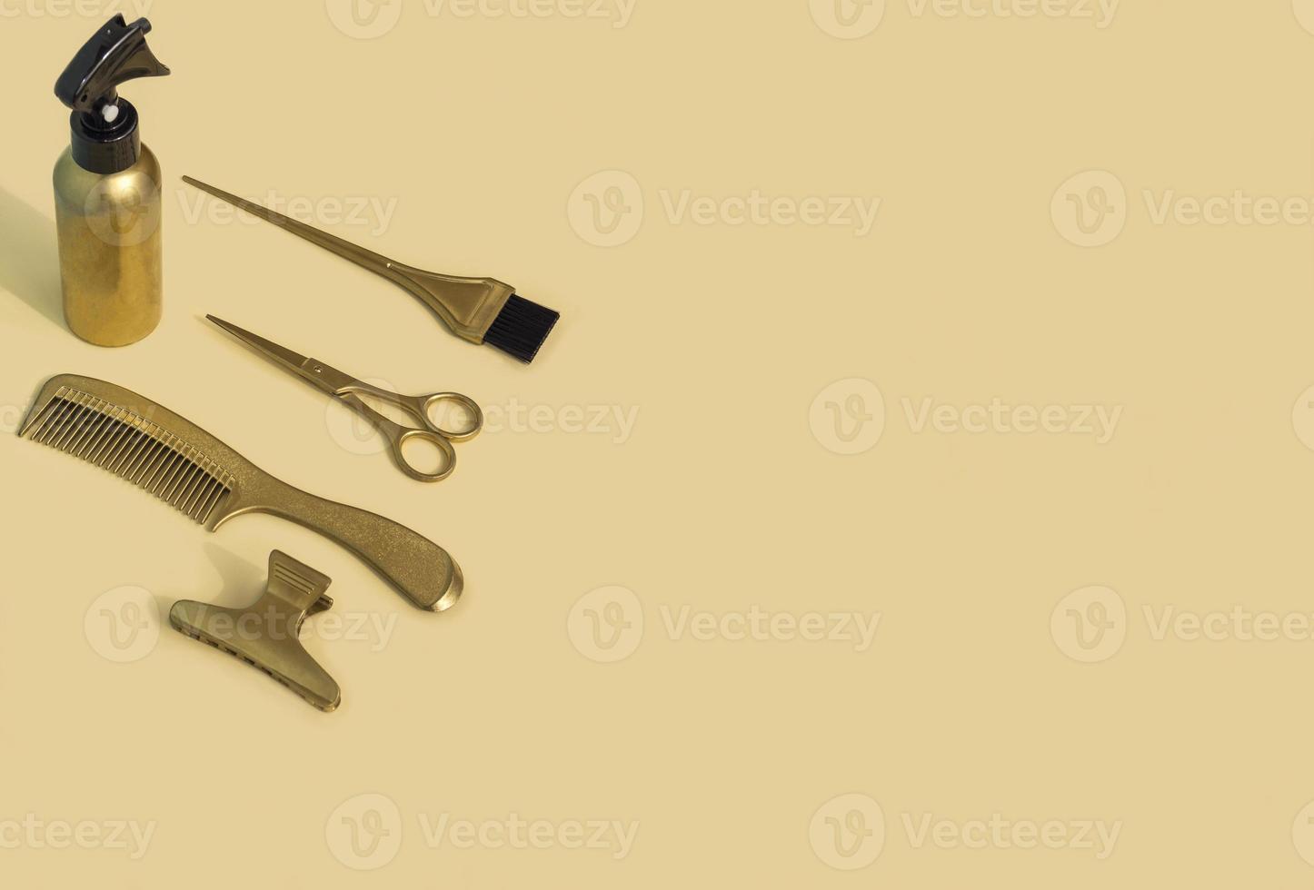 Gold hairdressing tools on a beige background. Template with hair salon accessories and space for text, top view. photo