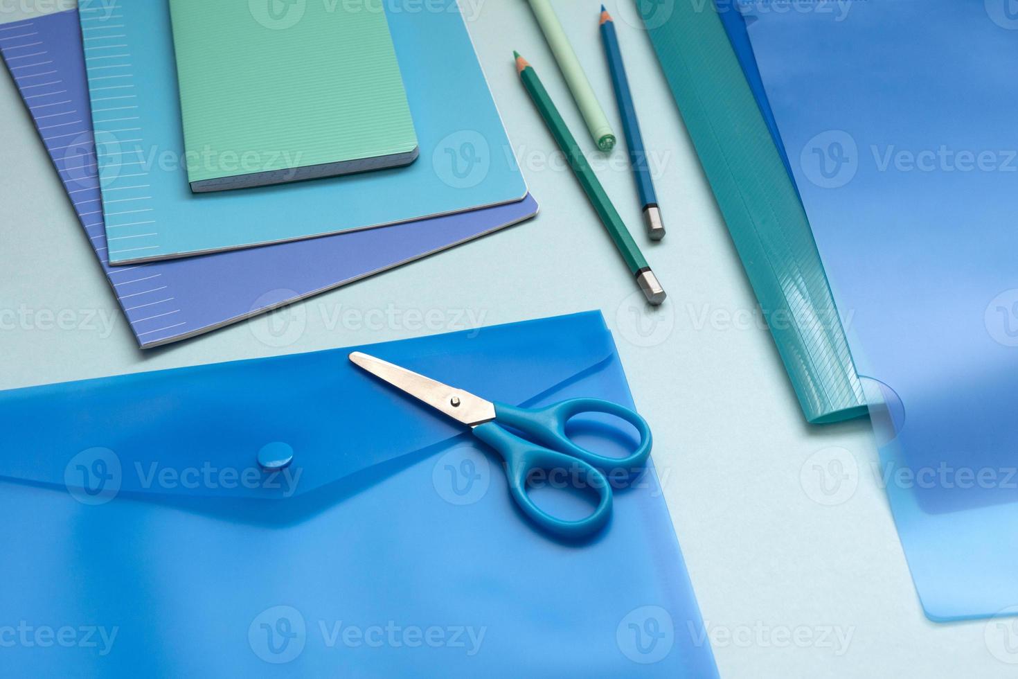 Background with blue office supplies. Folder, notebook, notebook, pencil in different shades of the same color. photo