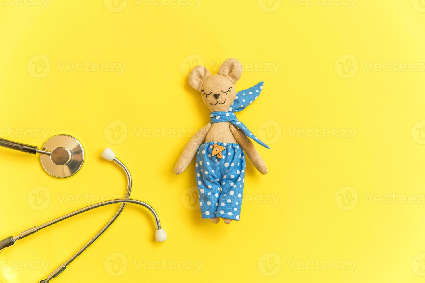 Simply minimal design toy bear and medicine equipment stethoscope isolated on yellow background. Health care children doctor concept. Pediatrician symbol. Flat lay top view layout, copy space photo