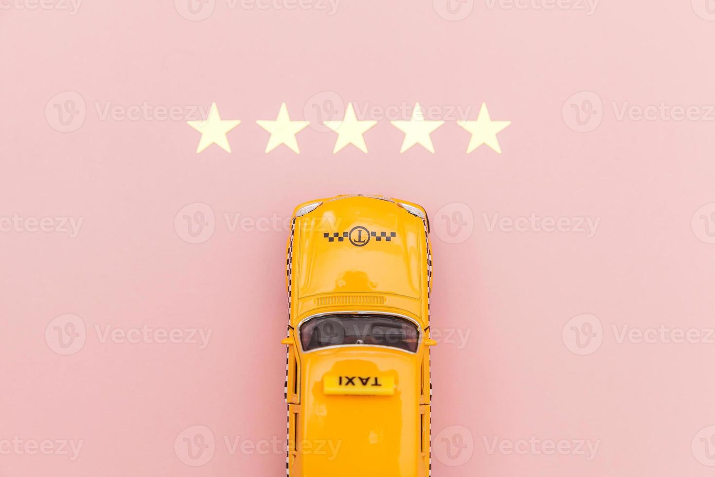 taxi de coche de juguete amarillo y calificación de 5 estrellas aislado sobre fondo rosa. aplicación de teléfono inteligente del servicio de taxi para buscar en línea llamadas y reservar el concepto de taxi. símbolo de taxi. copie el espacio foto