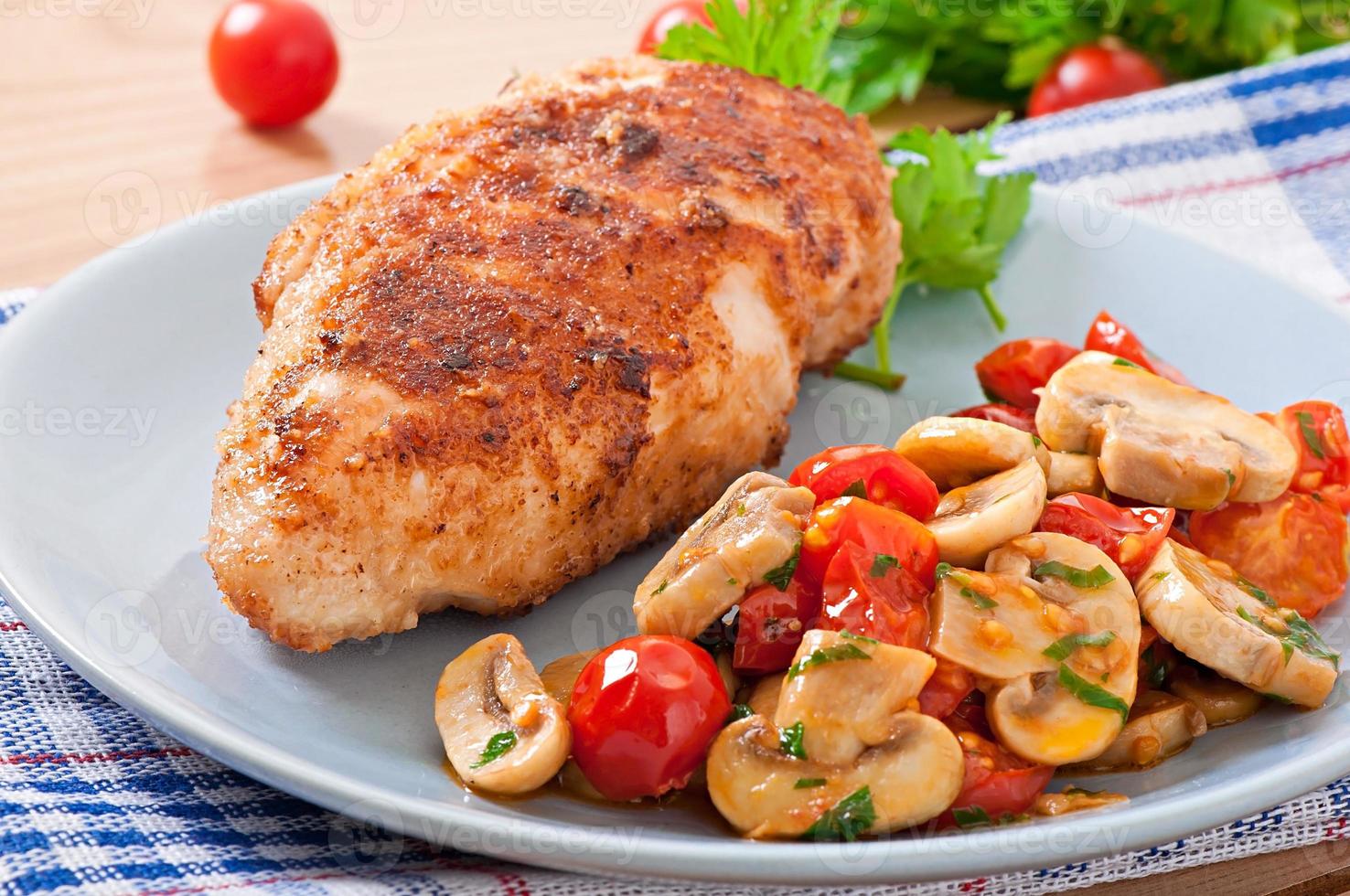 Chicken fillet in crispy breadcrumbs garnished with mushrooms and tomatoes photo