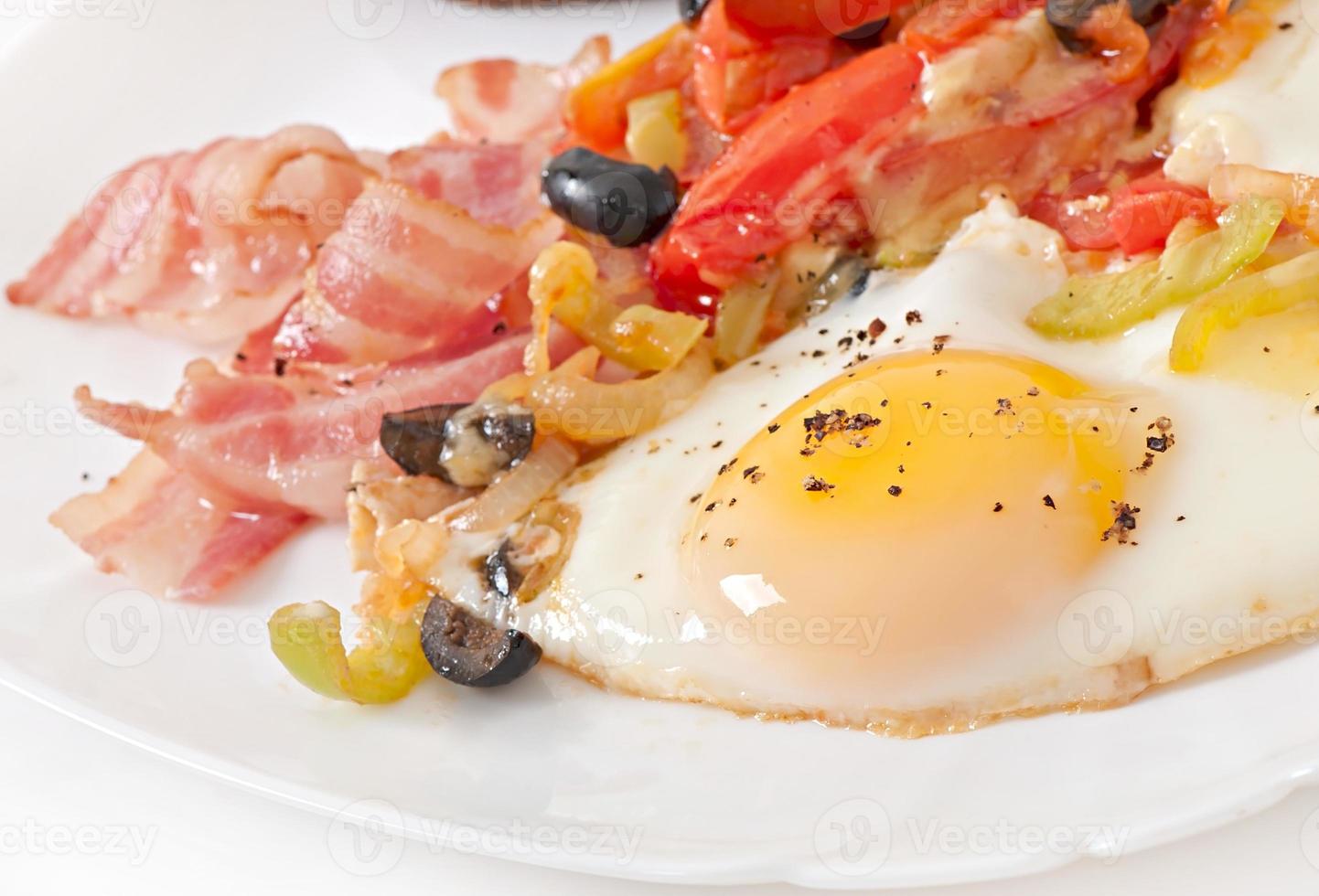 Breakfast - fried eggs with bacon, tomatoes, olives and slices of cheese photo