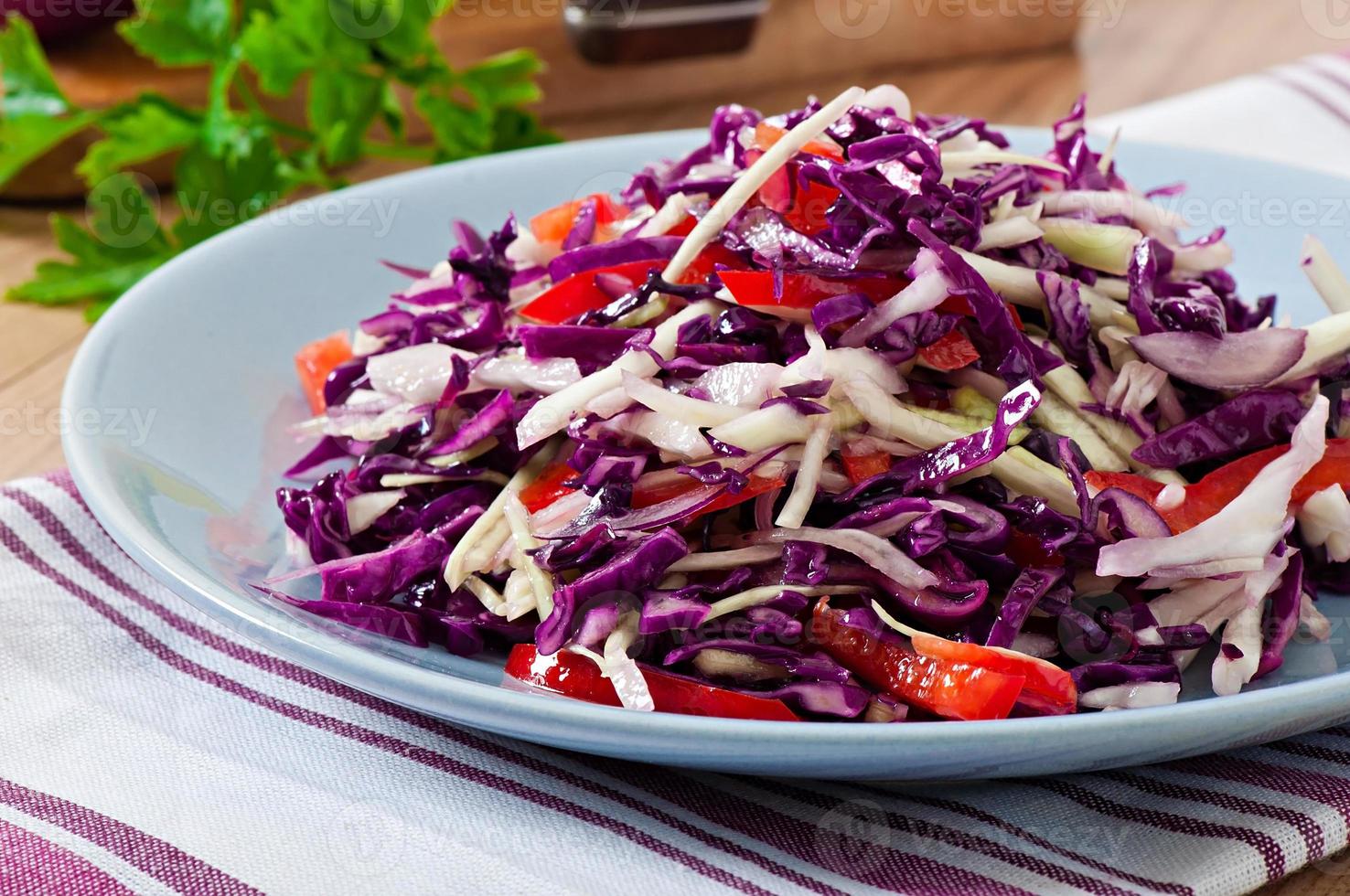 Salad of red and white cabbage and sweet red pepper, seasoned with lemon juice and olive oil in wooden bowl photo