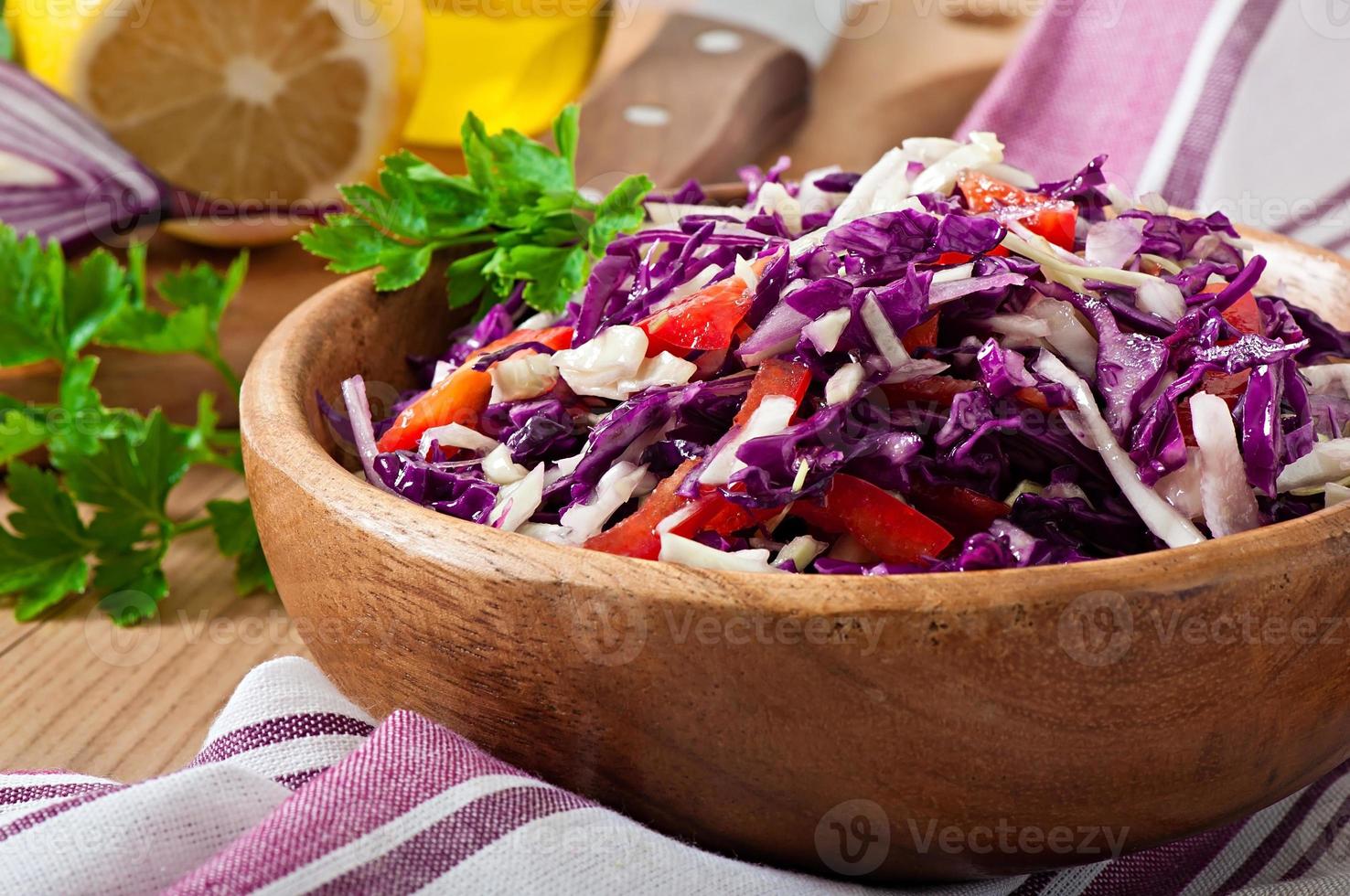 Salad of red and white cabbage and sweet red pepper, seasoned with lemon juice and olive oil in wooden bowl photo