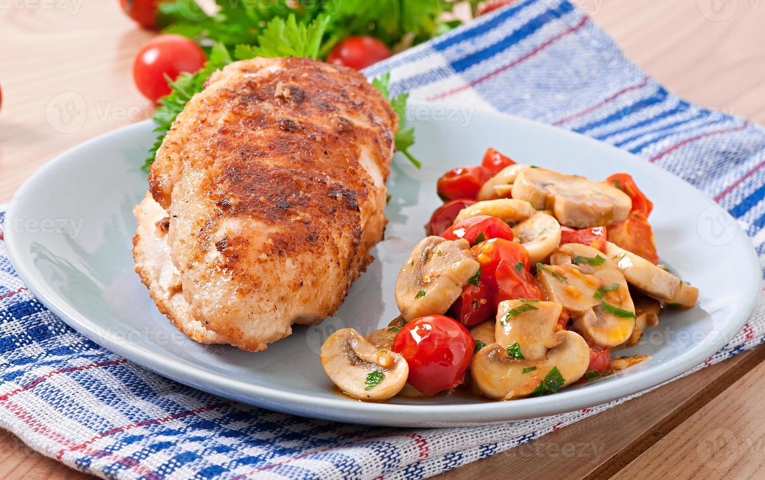 Chicken fillet in crispy breadcrumbs garnished with mushrooms and tomatoes photo