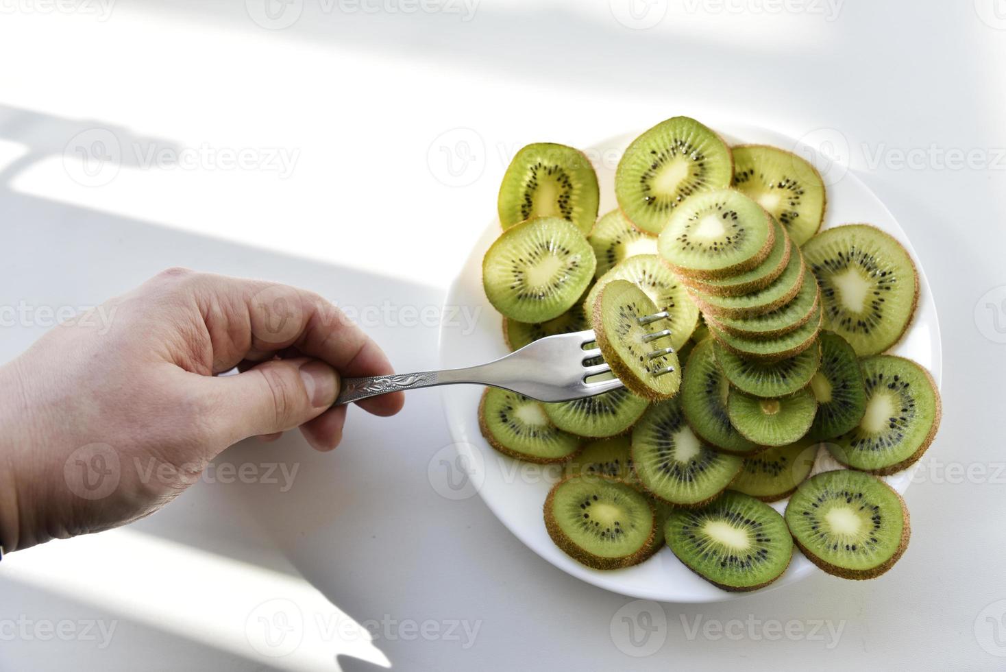 rodajas de kiwi en un plato blanco con un tenedor foto