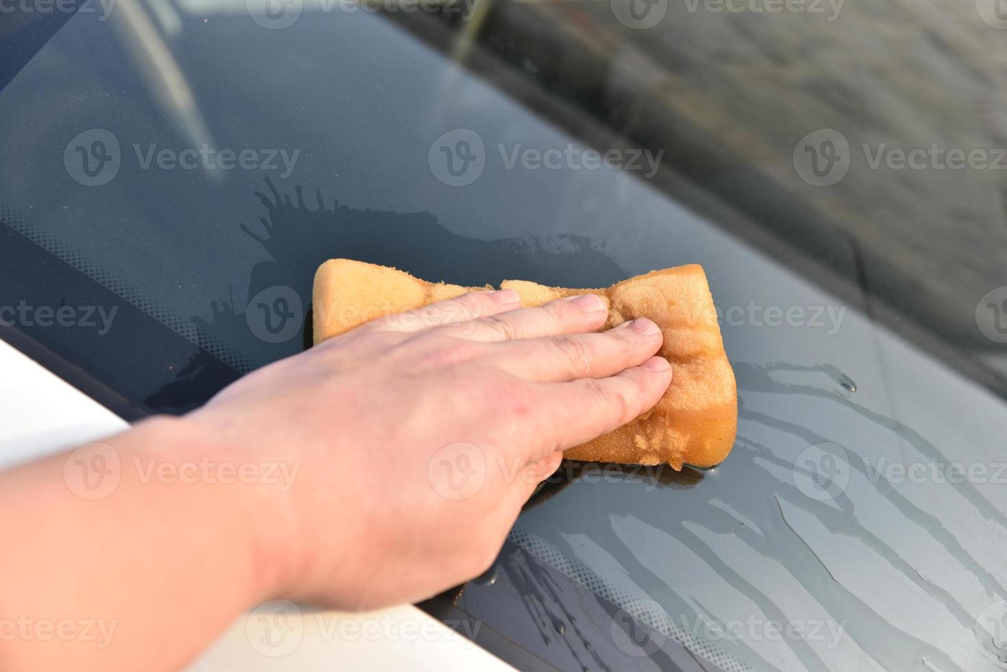 lavar un auto blanco con una esponja a mano foto