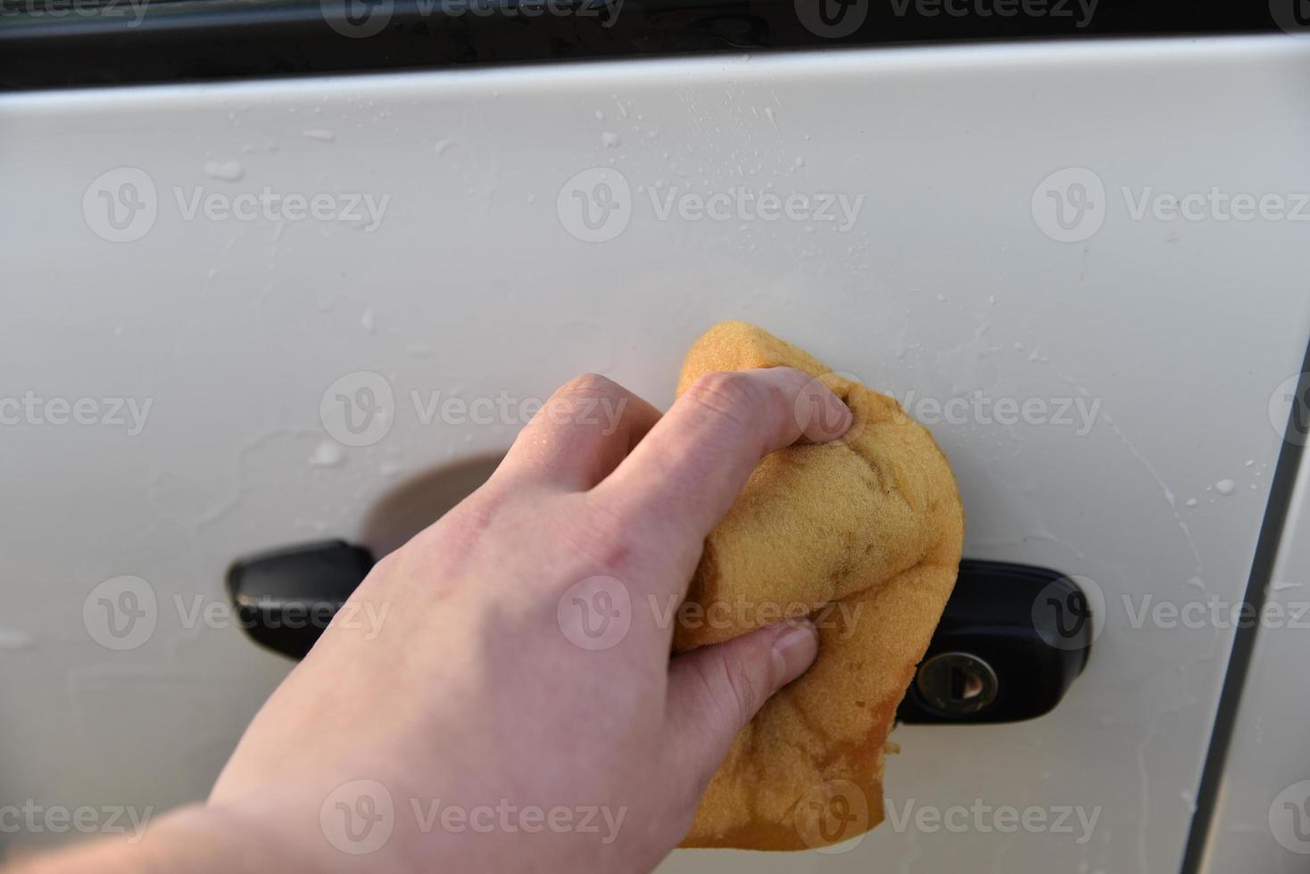 lavar un auto blanco con una esponja a mano foto