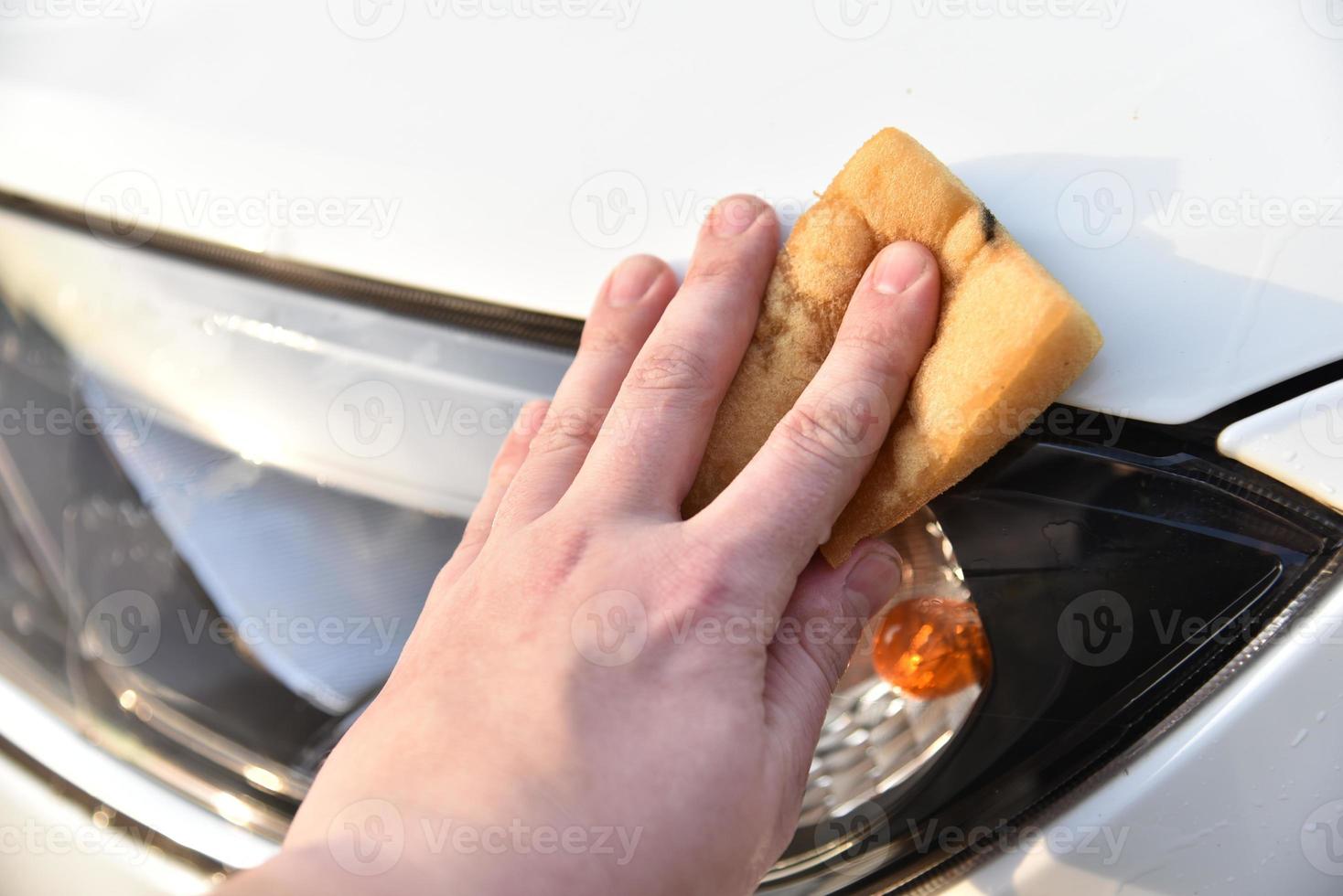 lavar un auto blanco con una esponja a mano foto