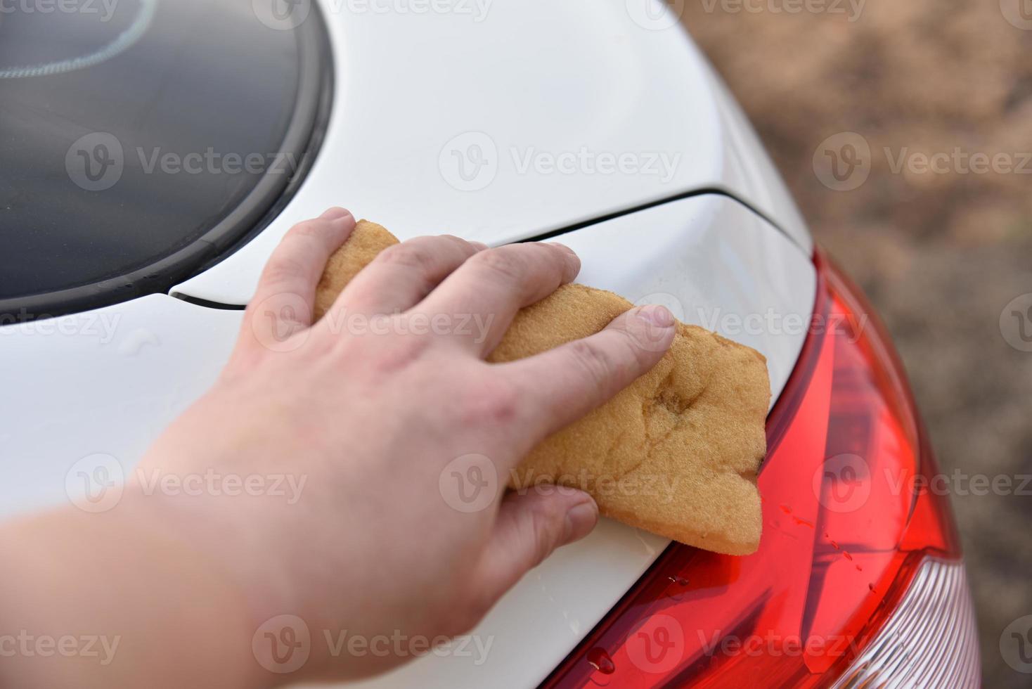 lavar un auto blanco con una esponja a mano foto