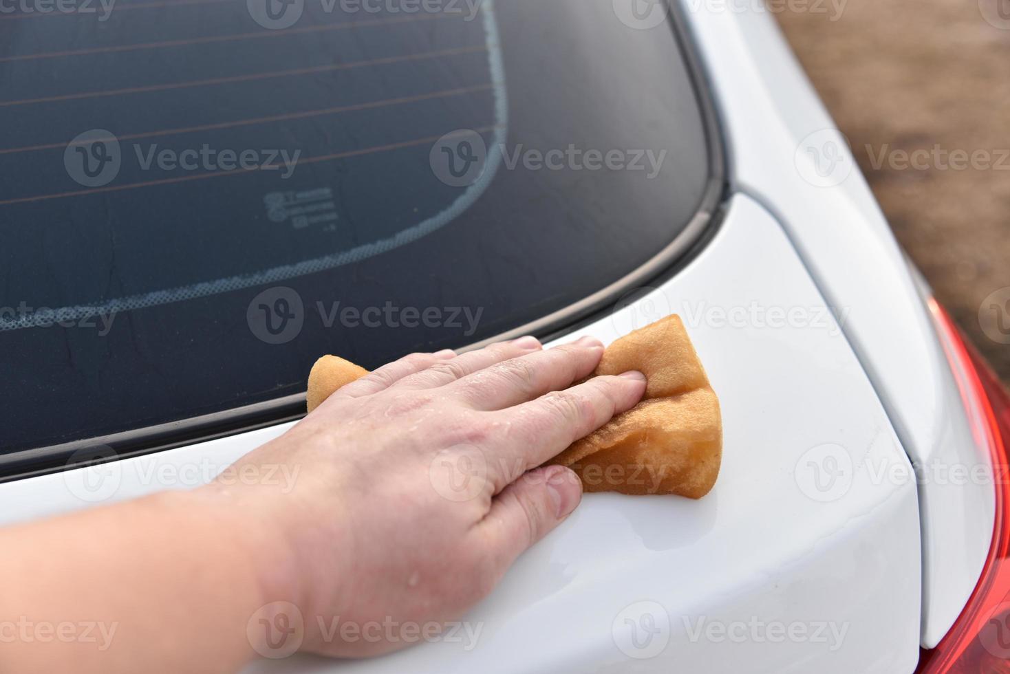 lavar un auto blanco con una esponja a mano foto