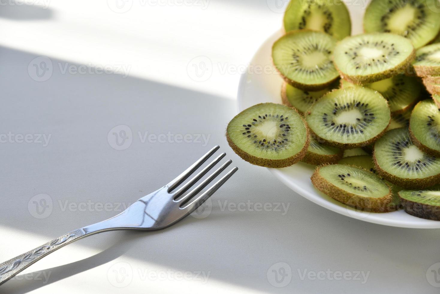 rodajas de kiwi en un plato blanco con un tenedor foto