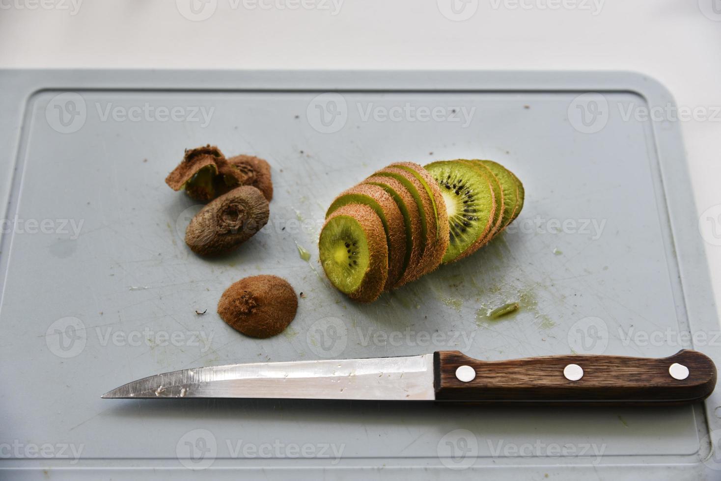 Slicing kiwi fruit with a knife on a board photo