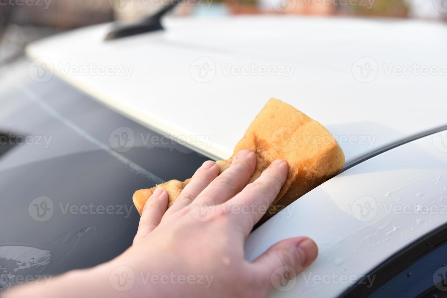 lavar un auto blanco con una esponja a mano foto