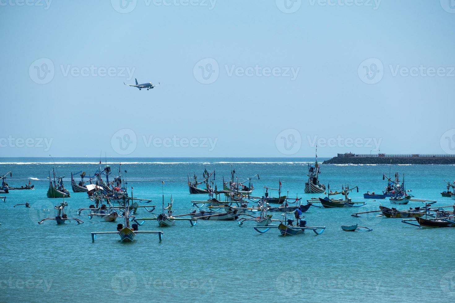 aterrizaje de avión en el aeropuerto y barco tradicional de pesca jukung en bali foto