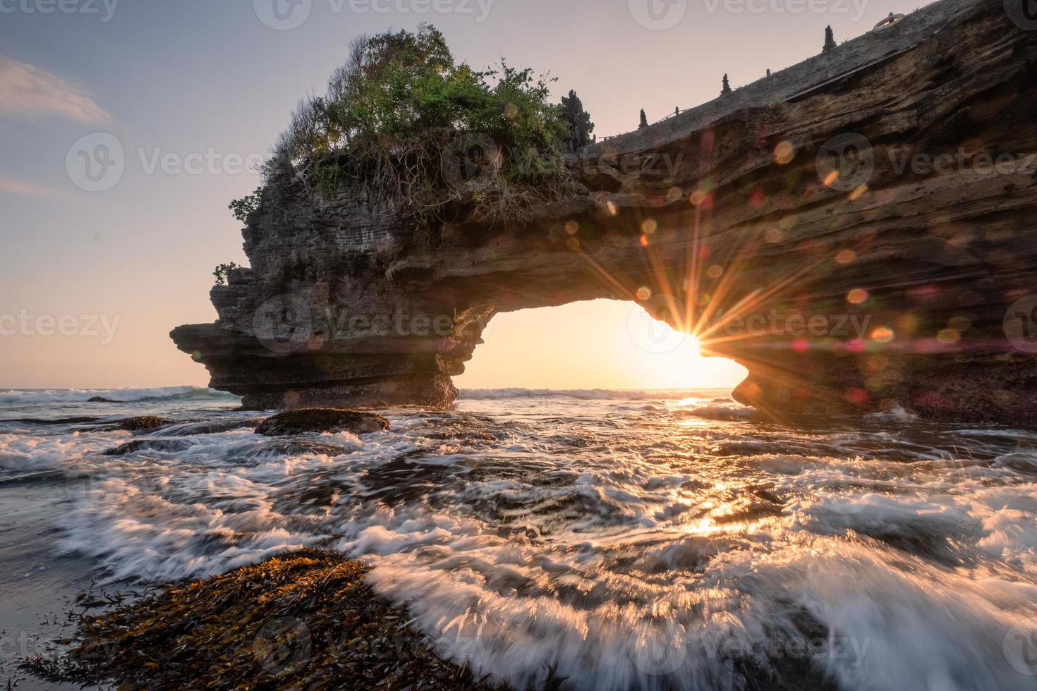 Sunshine through of rocky cliff on seashore at sunset photo