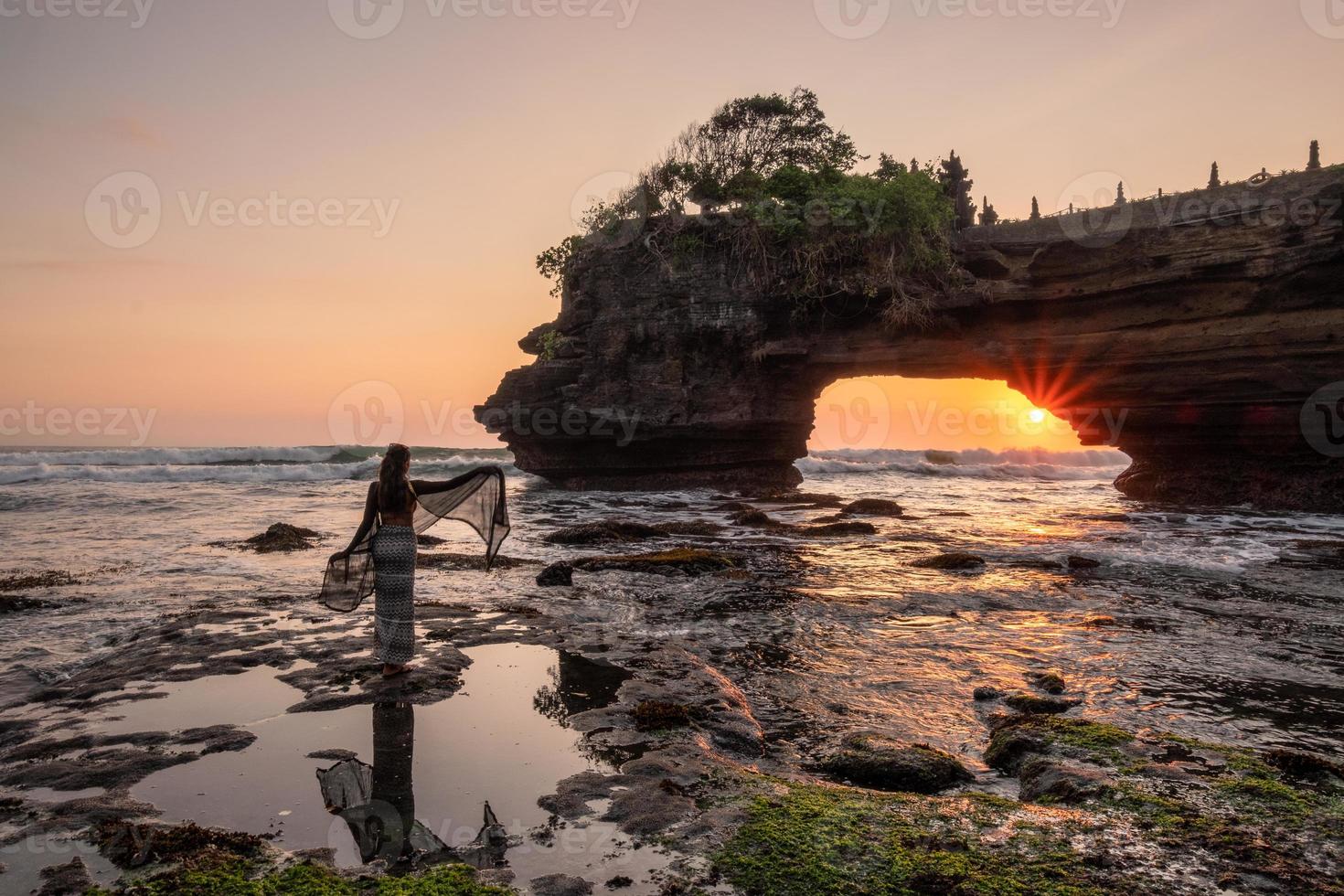 Tourist poses on seashore at sunset photo