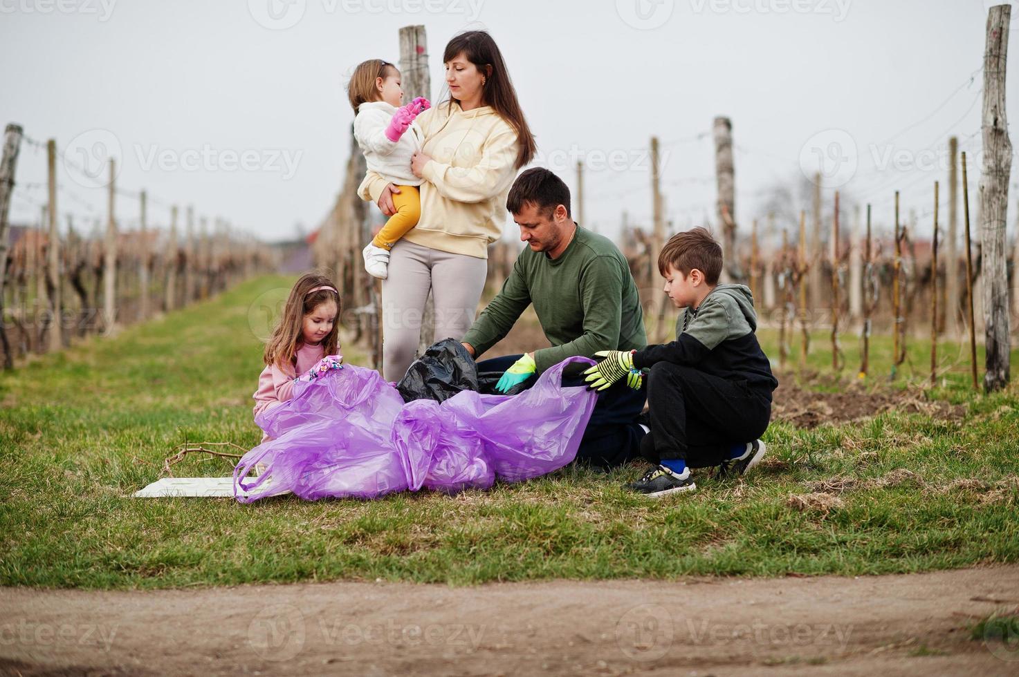 familia con bolsa de basura recogiendo basura mientras limpia en los viñedos. conservación ambiental y ecología, reciclaje. foto