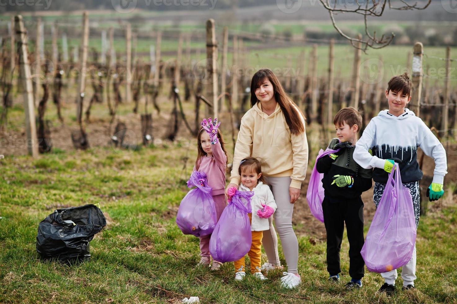 familia con bolsa de basura recogiendo basura mientras limpia en los viñedos. conservación ambiental y ecología, reciclaje. foto