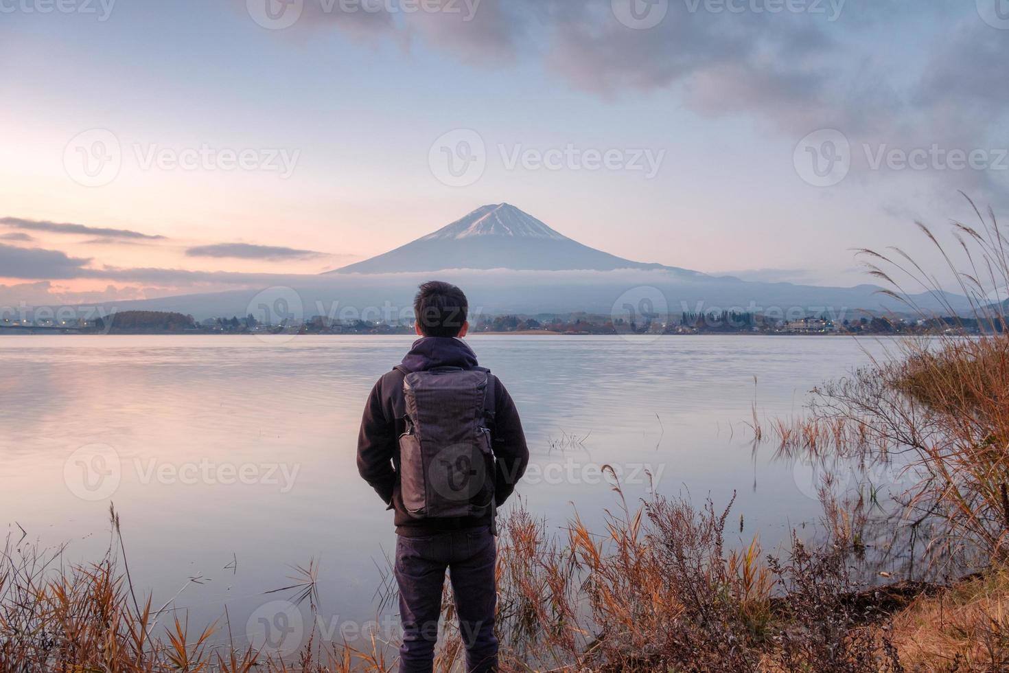 Young asian man stand looking Mount Fuji on Kawaguchiko Lake at dawn photo