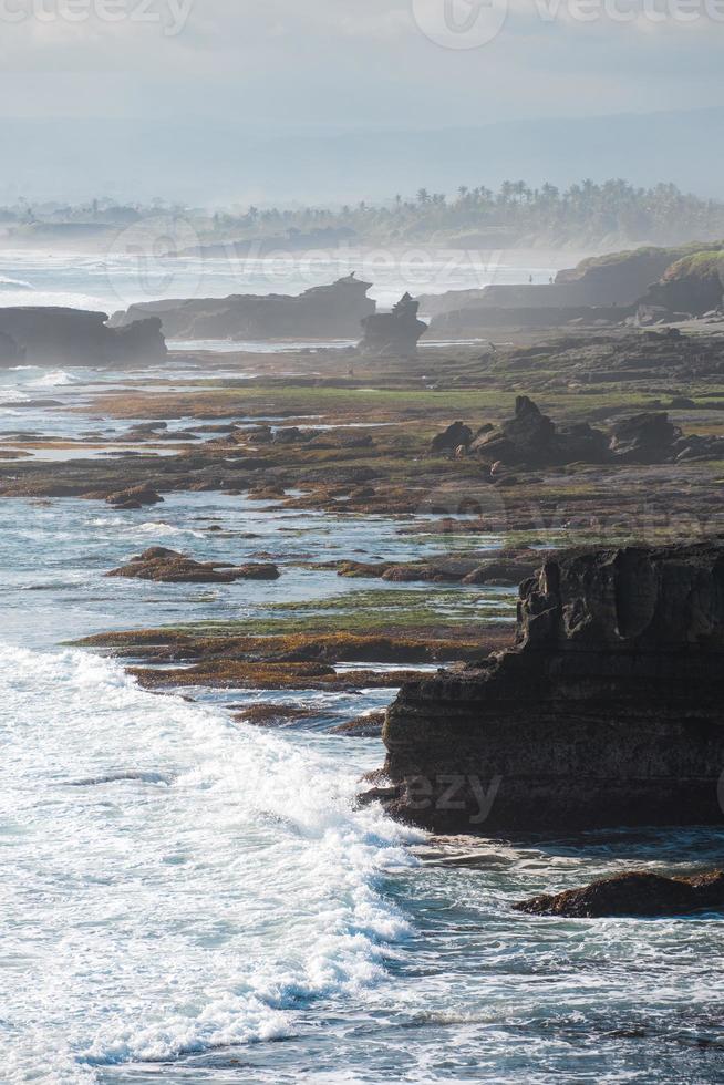 Natural rock cliff near Pura Batu Bolong temple with wave hitting on coastline at Bali photo