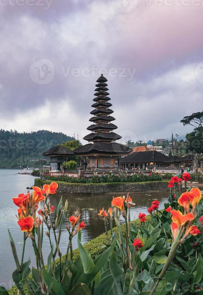 Ancient Pura Ulun Danu Bratan temple with orange flower blooming at Bali photo