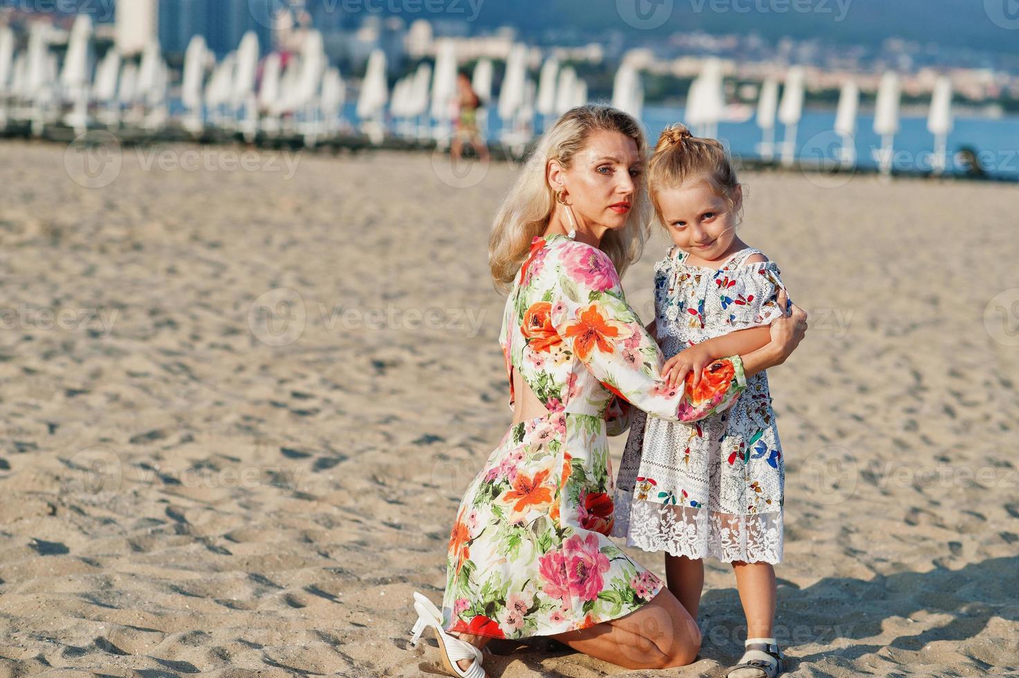 Mother and beautiful daughter having fun on the beach. Portrait of happy woman with cute little girl on vacation. photo