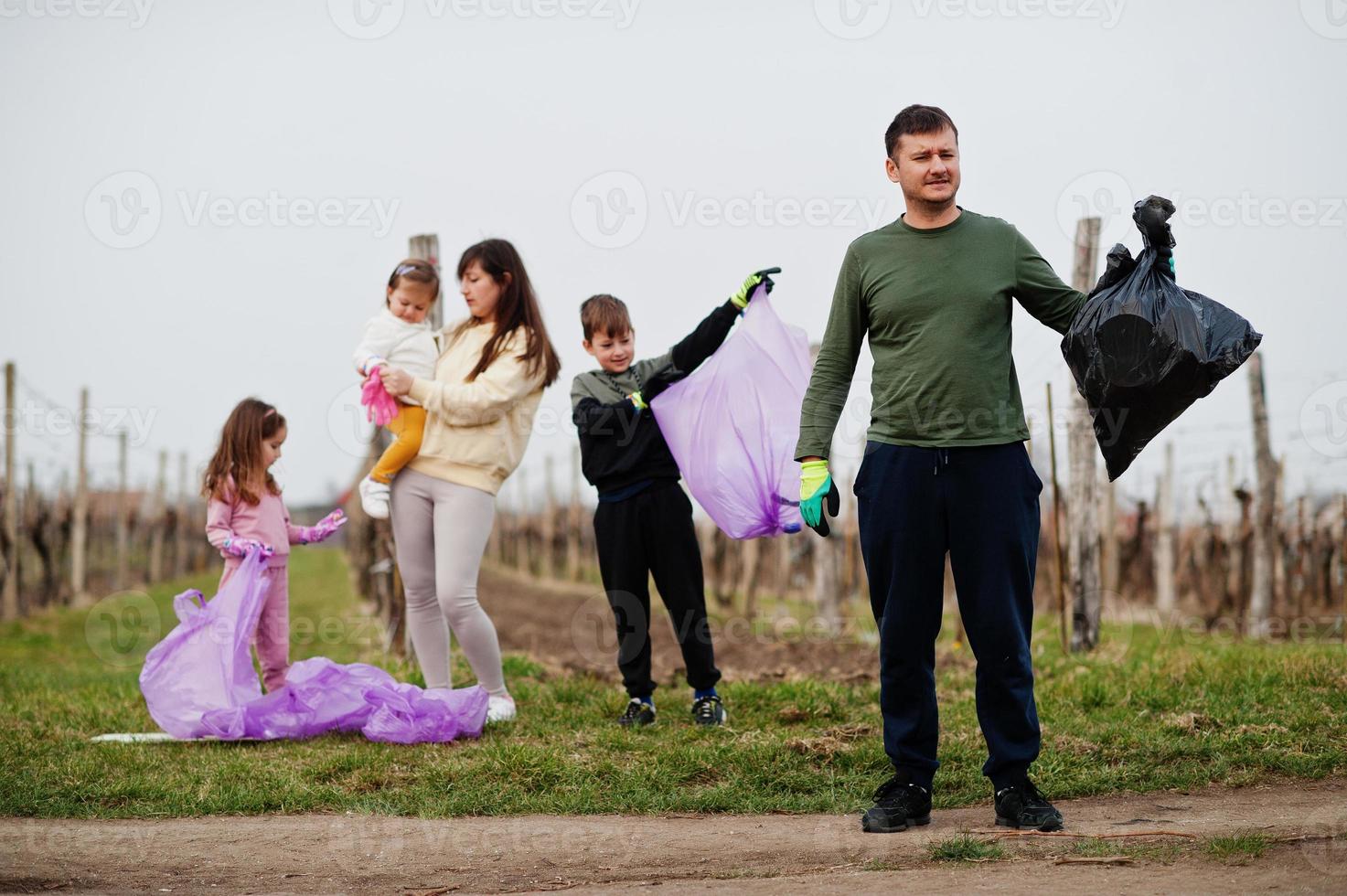 familia con bolsa de basura recogiendo basura mientras limpia en los viñedos. conservación ambiental y ecología, reciclaje. foto