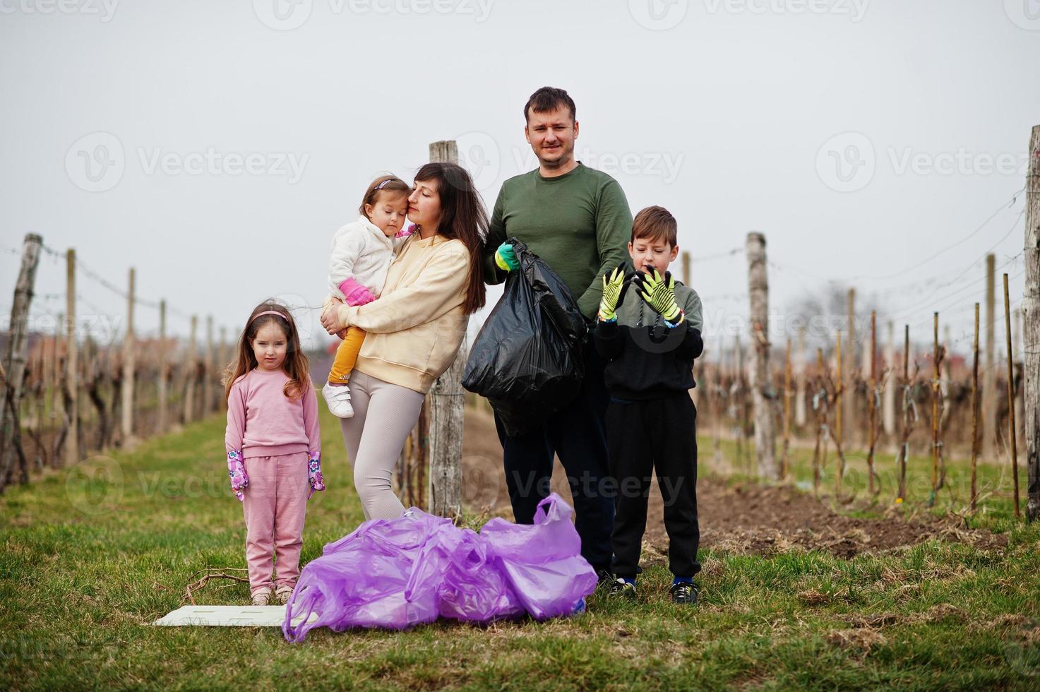 Family with trash bag collecting garbage while cleaning in the vineyards . Environmental conservation and ecology, recycling. photo